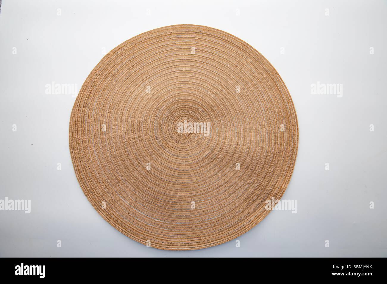 Runder Tischset mit Strohhalm mit konzentrischem Muster auf weißem Hintergrund, umweltfreundliche Einrichtung für Küche und Esszimmer, Blick von oben. Stockfoto