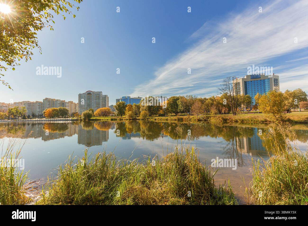 Herbstteich oder Teil des Flusses mit Reflexion des Himmels und der Gebäude. Stadtsee im Herbst im Park. Stockfoto