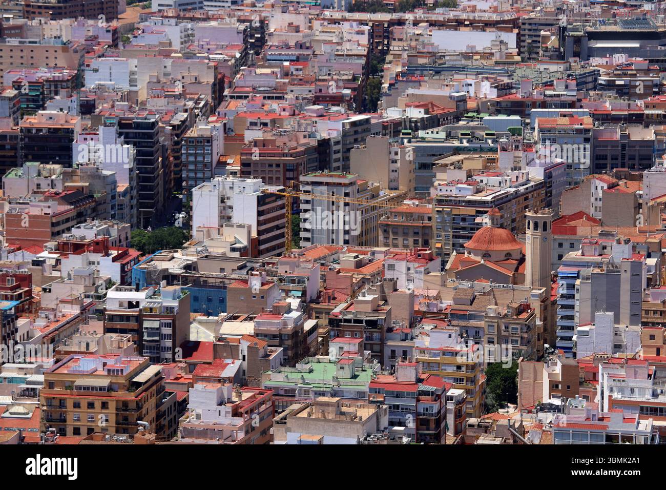 Panoramablick auf die Stadt Alicante mit Stierkampfarena, städtischen Gebäuden und Bergen im Hintergrund unter klarem Himmel. Stockfoto