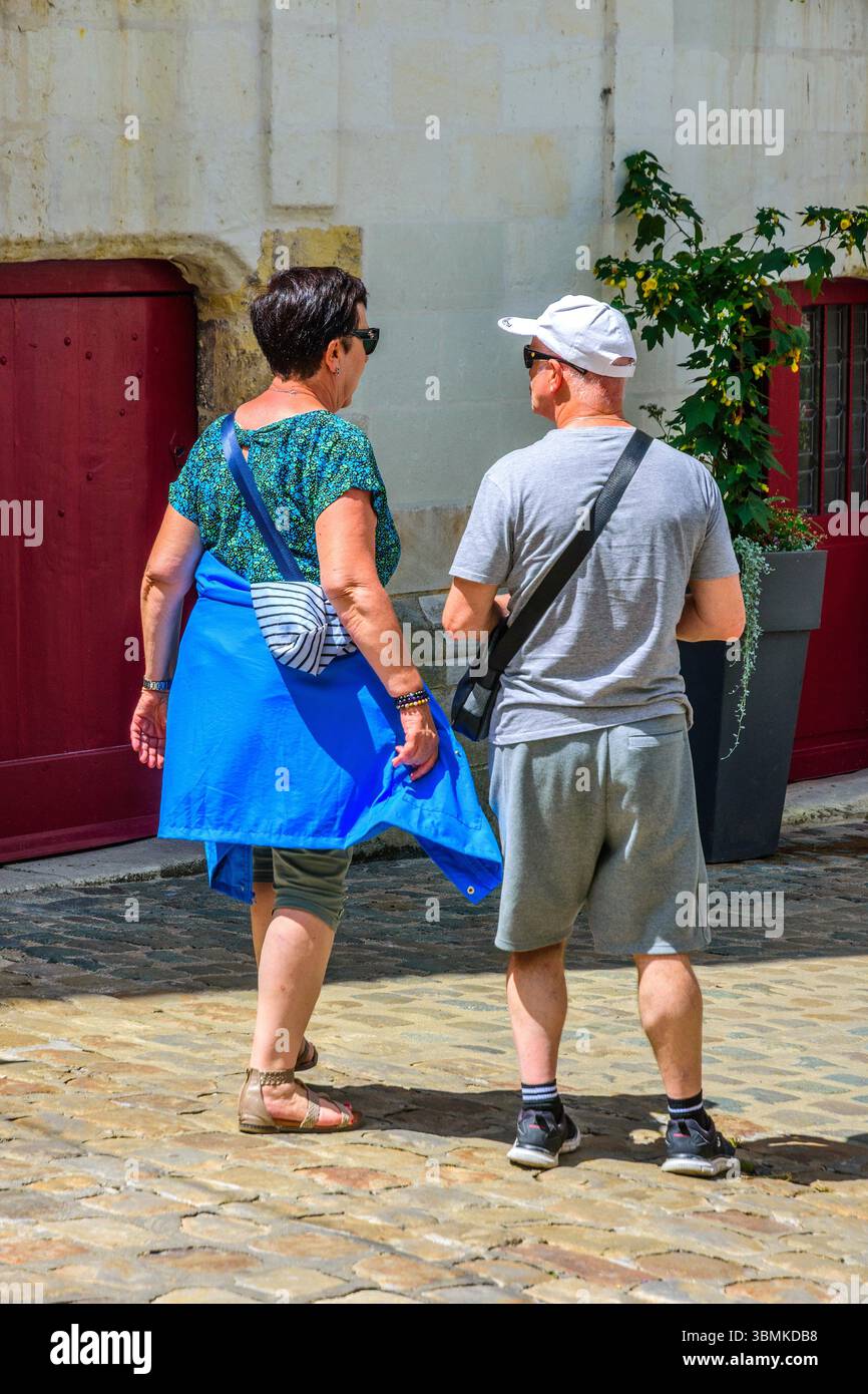 Touristen-Paar in Sommerkleidung zu Fuß auf der Kopfsteinpflasterstraße in der Altstadt - Loches, Indre-et-Loire (37), Frankreich. Stockfoto