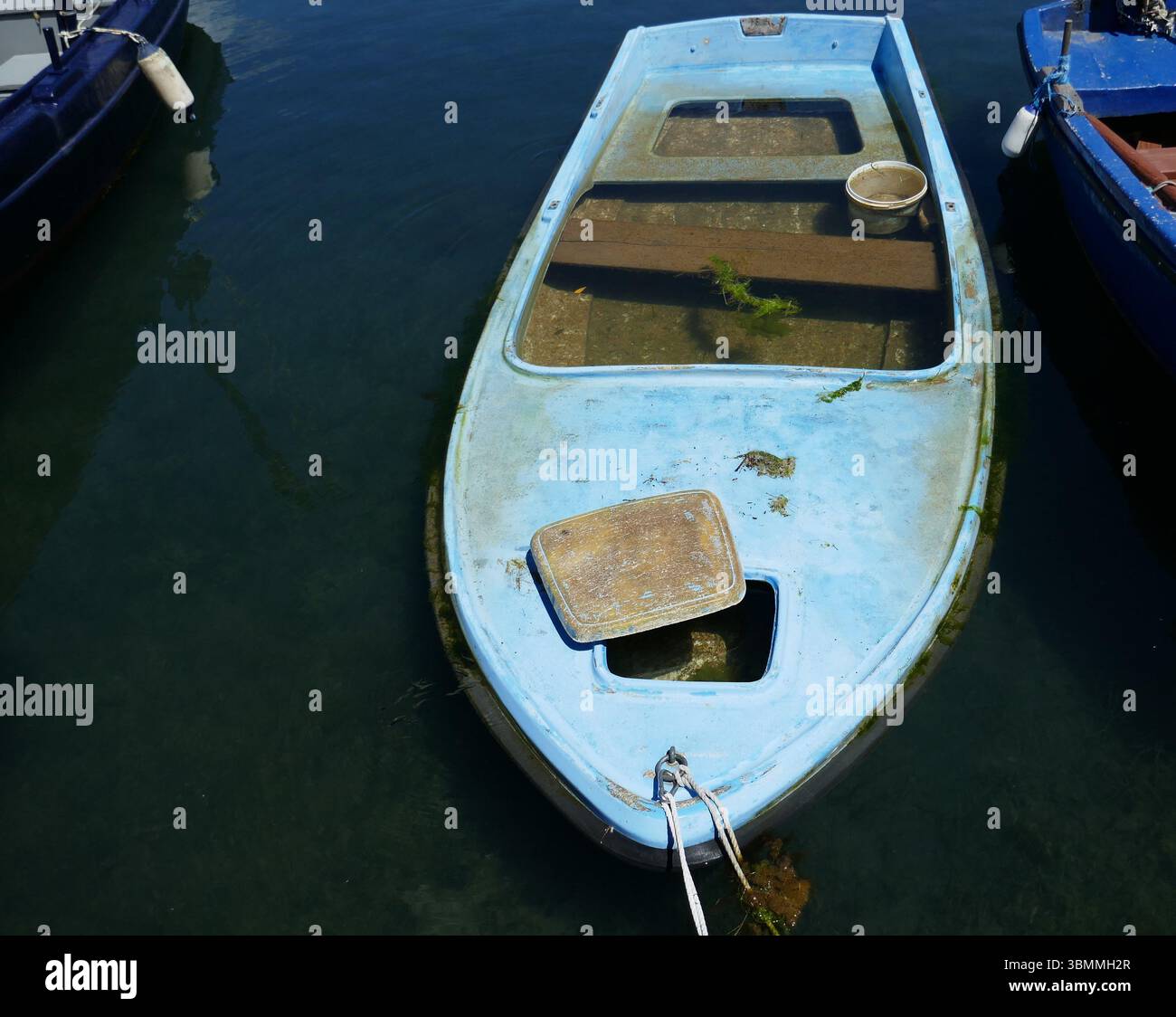 Marina mit eingesunkenem blauem Boot voller Wasser Stockfoto