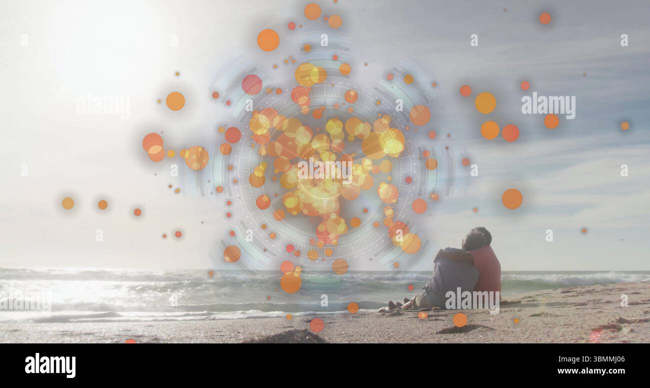 Sitzendes älteres Paar in farbenfrohen Jacken am Meeresstrand, mit orangefarbener digitaler Überlagerung, Kopierraum Stockfoto