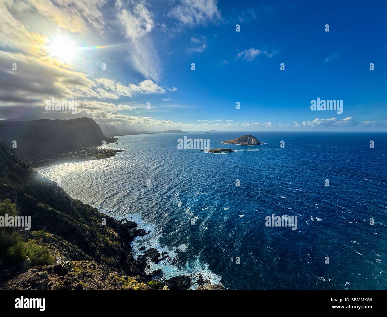 Vom Makapuu Lighthouse, Oahu, aus atemberaubender Vogelperspektive auf Rabbit Island – türkisfarbene Wellen des Pazifiks stürzen entlang der dramatischen Vulkanküste und des lebendigen Himmels Stockfoto