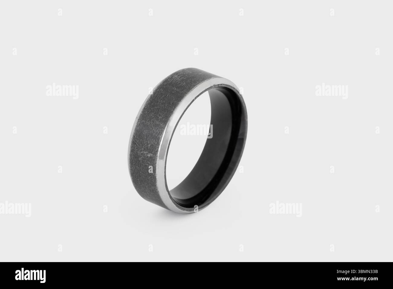 Schwarzer Fingerring aus Edelstahl isoliert auf weißem Hintergrund mit Bokeh Stockfoto