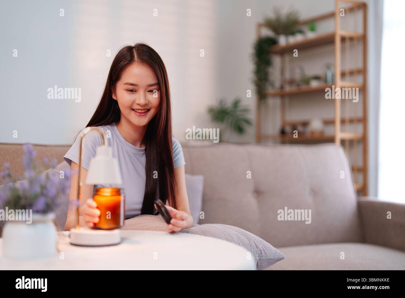 Asiatische junge Frau schafft ein beruhigendes Zuhause Ambiente mit Aromatherapie Diffusor fördert Tiefenentspannung geistiges Wohlbefinden ganzheitliche Gesundheit Stockfoto