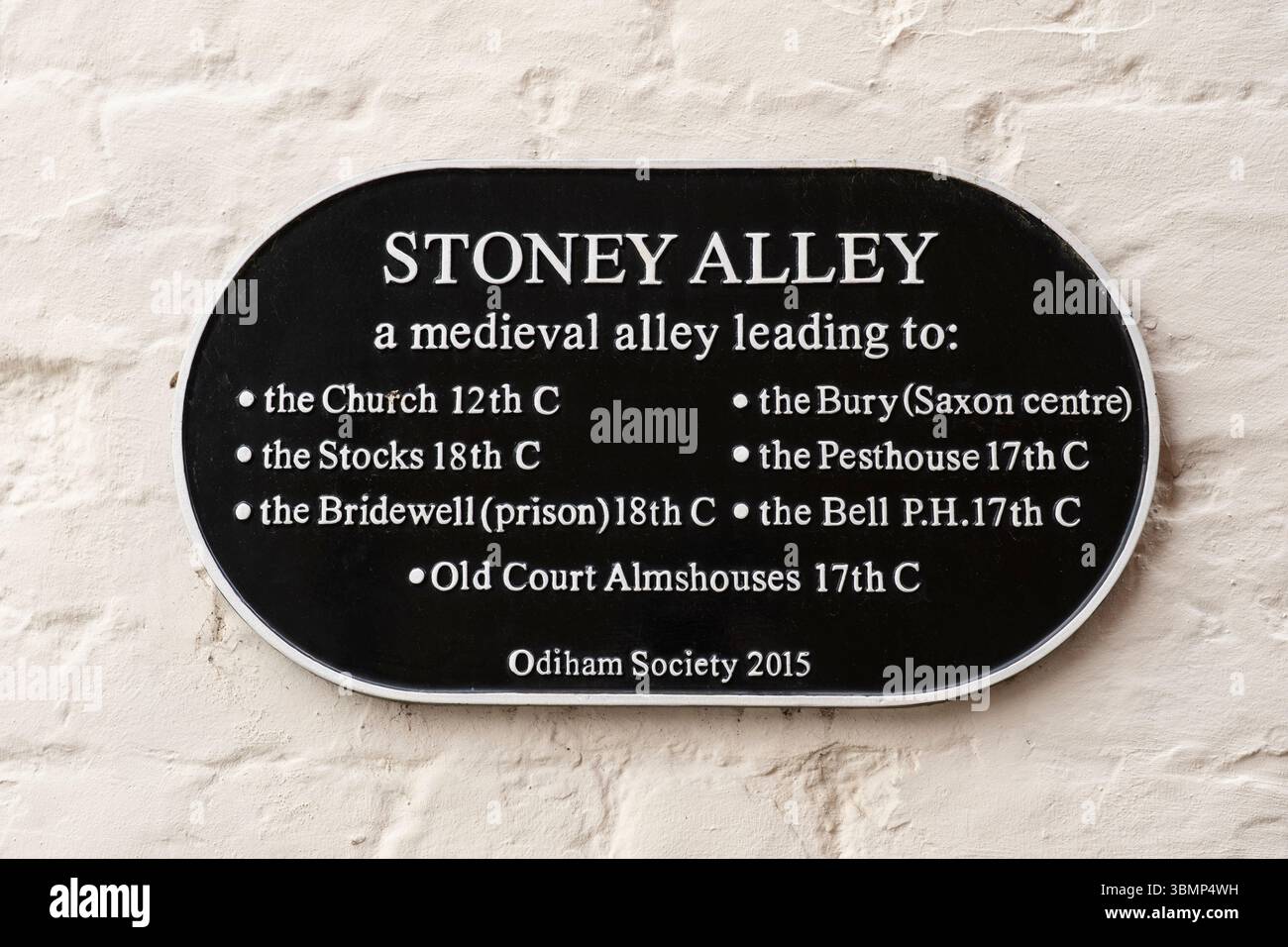 Die Stoney Alley, die hier mit einer Gedenktafel der Odiham Society markiert ist, ist eine mittelalterliche Passage, die zwischen der Odiham High Street und der All Saints Church in Großbritannien führt Stockfoto Die Stoney Alley, die hier mit einer Gedenktafel der Odiham Society markiert ist, ist eine mittelalterliche Passage, die zwischen der Odiham High Street und der All Saints Church in Großbritannien führt Stockfoto