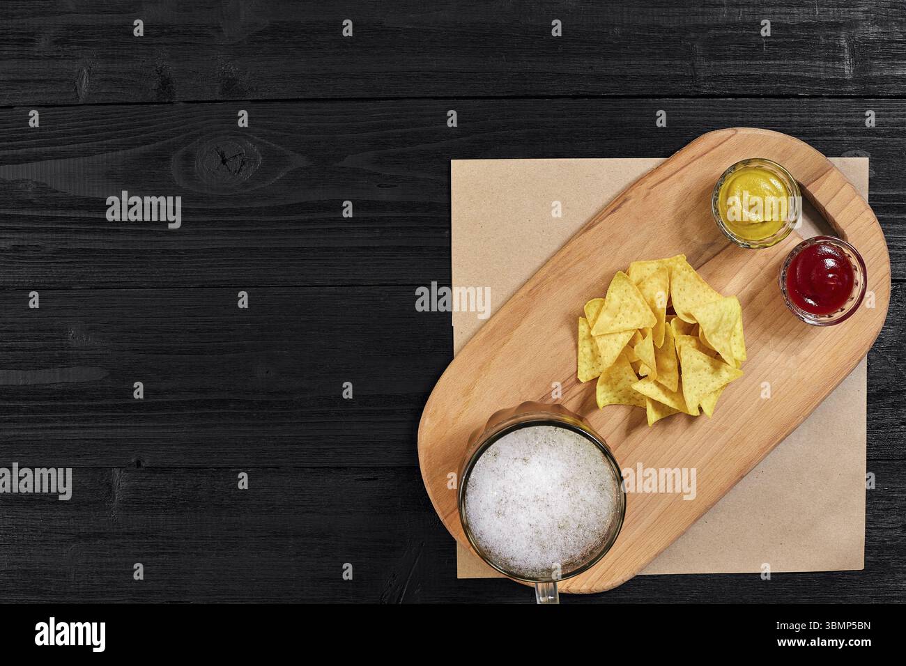 Glas Bier mit Nachos-Chips auf Holzhintergrund. Draufsicht. Speicherplatz kopieren. Stillleben. Flach liegend Stockfoto