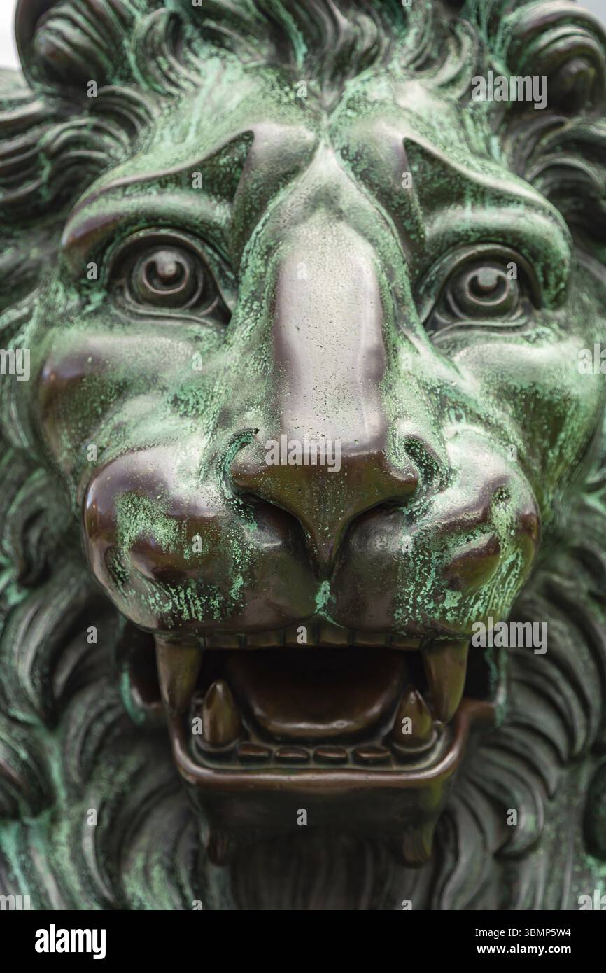 Löwenstatue alt. Nahaufnahme des Kopfes einer Bronzeskulptur eines Löwen. Große bronzene Löwenstatue im Außenbereich Stockfoto