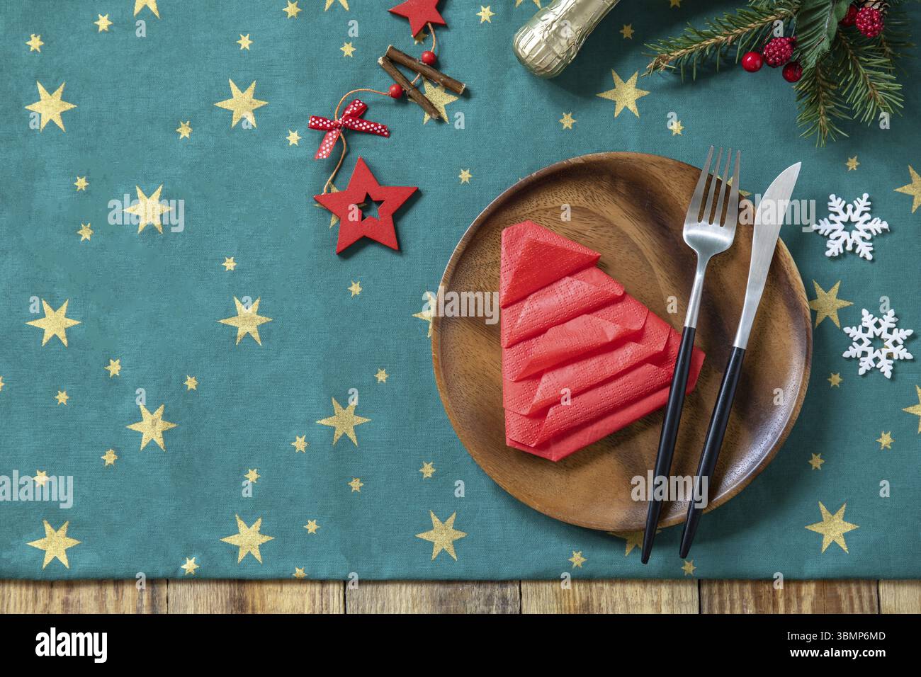 Tischgestaltung für Weihnachtsessen, Weihnachtszusammensetzung. Tischgabel- und Messerset mit roter Papierserviette und Tannenzweig auf einem rustikalen Festtisch. Bis Stockfoto