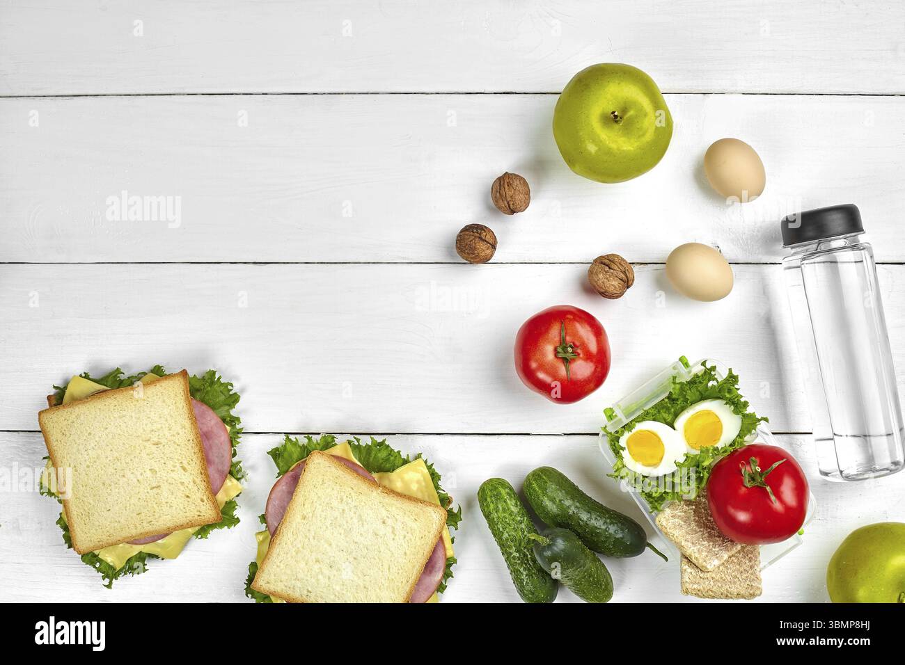 Mittagessen. Sandwich und frisches Gemüse, eine Flasche Wasser, Nüssen und Früchten auf weißem Holz- Hintergrund. Gesunde Ernährung Konzept. Ansicht von oben mit der Kopie. S Stockfoto