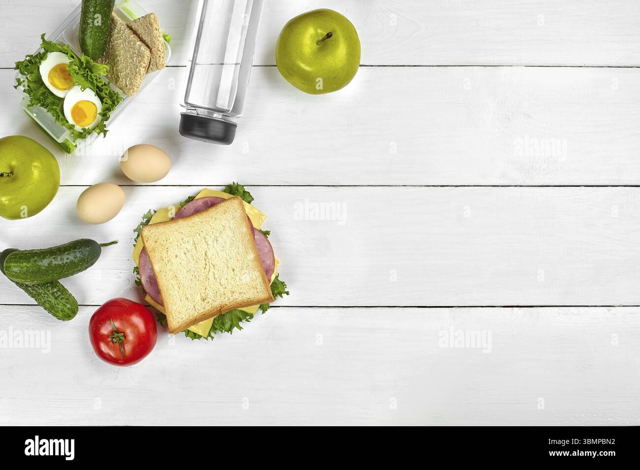 Mittagessen. Sandwich und frisches Gemüse, eine Flasche Wasser und grüner Apfel auf hölzernen Tisch. Gesunde Ernährung Konzept. Ansicht von oben. Immer noch leben. Flach. Kopieren Sie sp Stockfoto