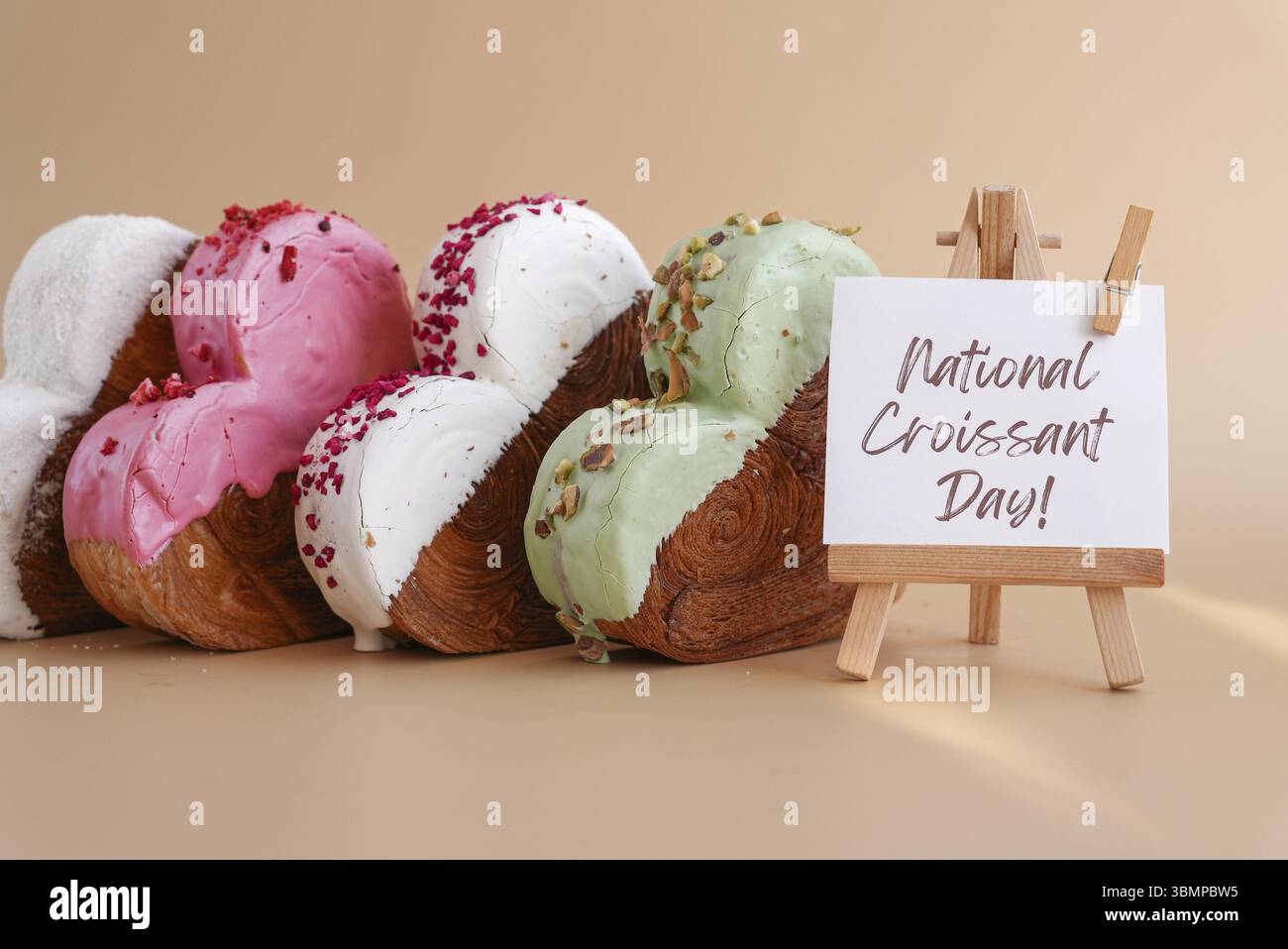 Feiertagsfeier NATIONALER CROISSANT-TAG Text Herz geformt verschiedene Vielfalt Geschmack Croissants auf beigem Hintergrund mit Kopierraum. Blätterteig neu Stockfoto