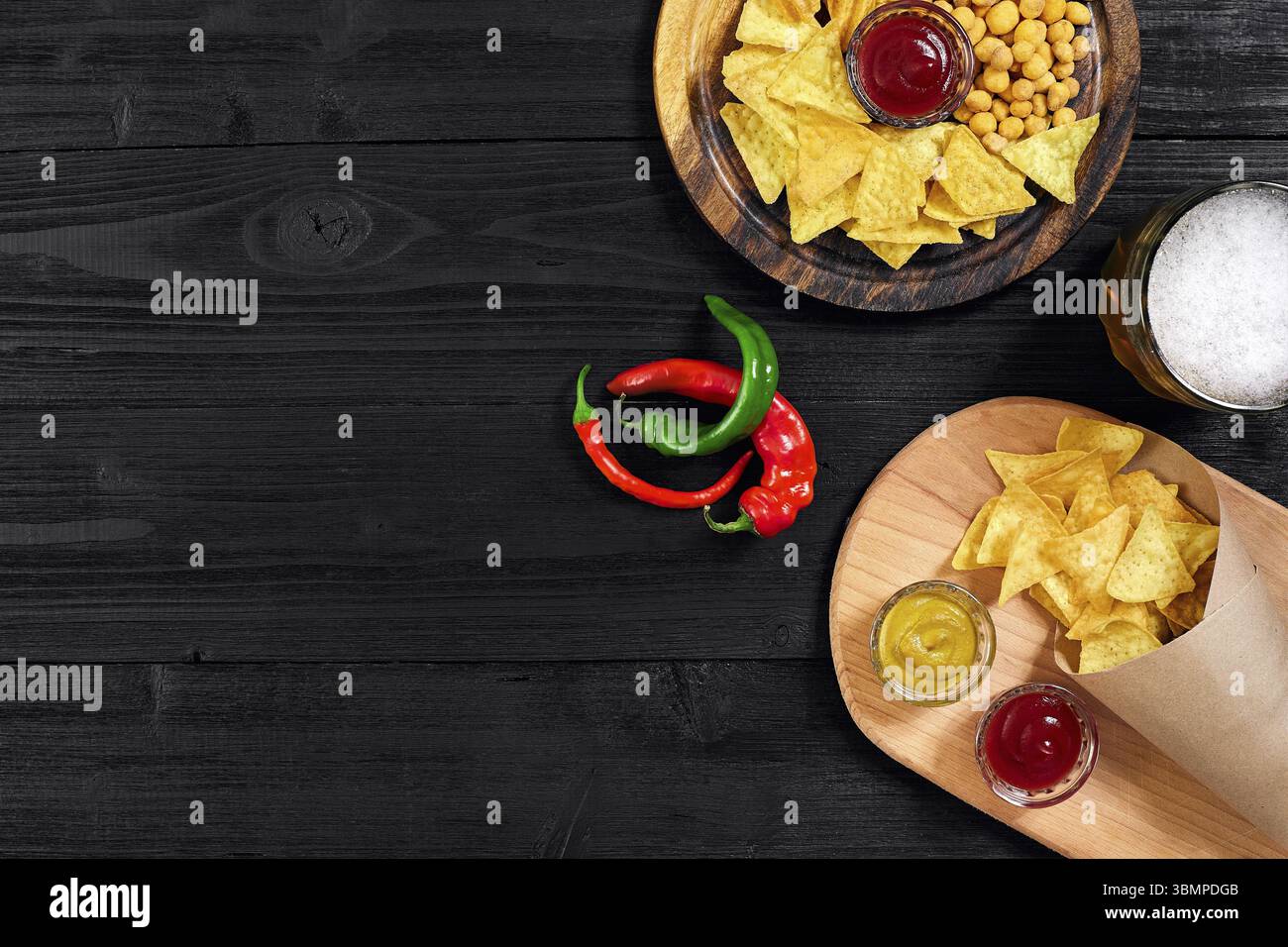Lagerbier und Snacks auf schwarzem Holztisch. Nüsse, Späne. Draufsicht mit Copyspace. Stillleben. Flach liegend Stockfoto