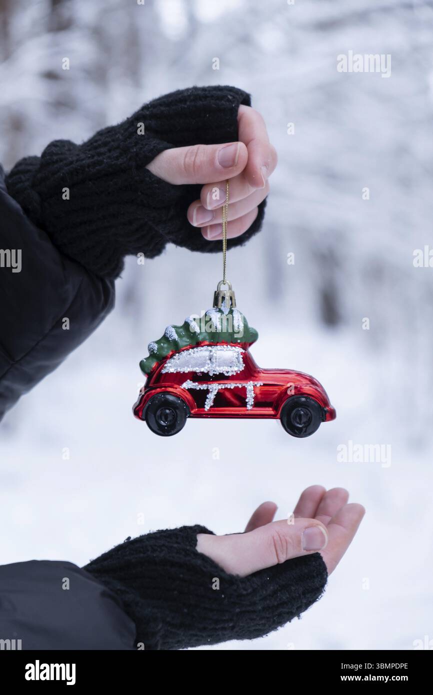 Weibliche Hände halten Weihnachtsdekoration im verschneiten Winterwald. Postkarte Grußkarte Mock Up. Urlaub Auto Spielzeugzweig Ornamente Neujahr ce Stockfoto