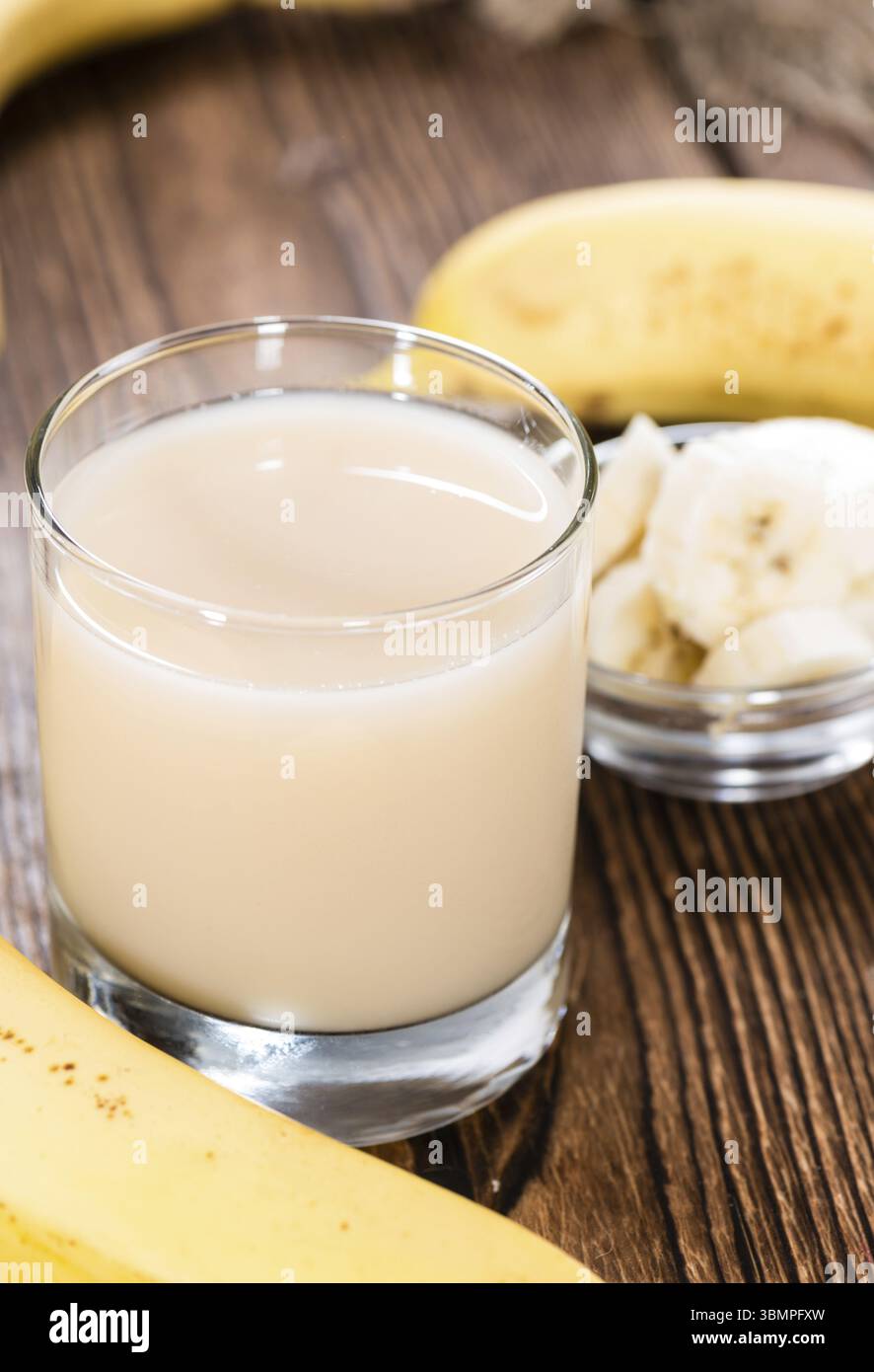 Glas mit Bananensaft auf Vintage Holz-Hintergrund (close-up erschossen) Stockfoto
