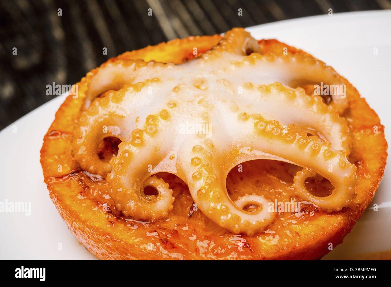 Meeresfrüchte. Kleine Krake auf einer Orangenscheibe gebacken. Nahaufnahme. Hohe Küche. Festes Futter vom Koch. Draufsicht. Speicherplatz kopieren. Stillleben. Flach liegend Stockfoto