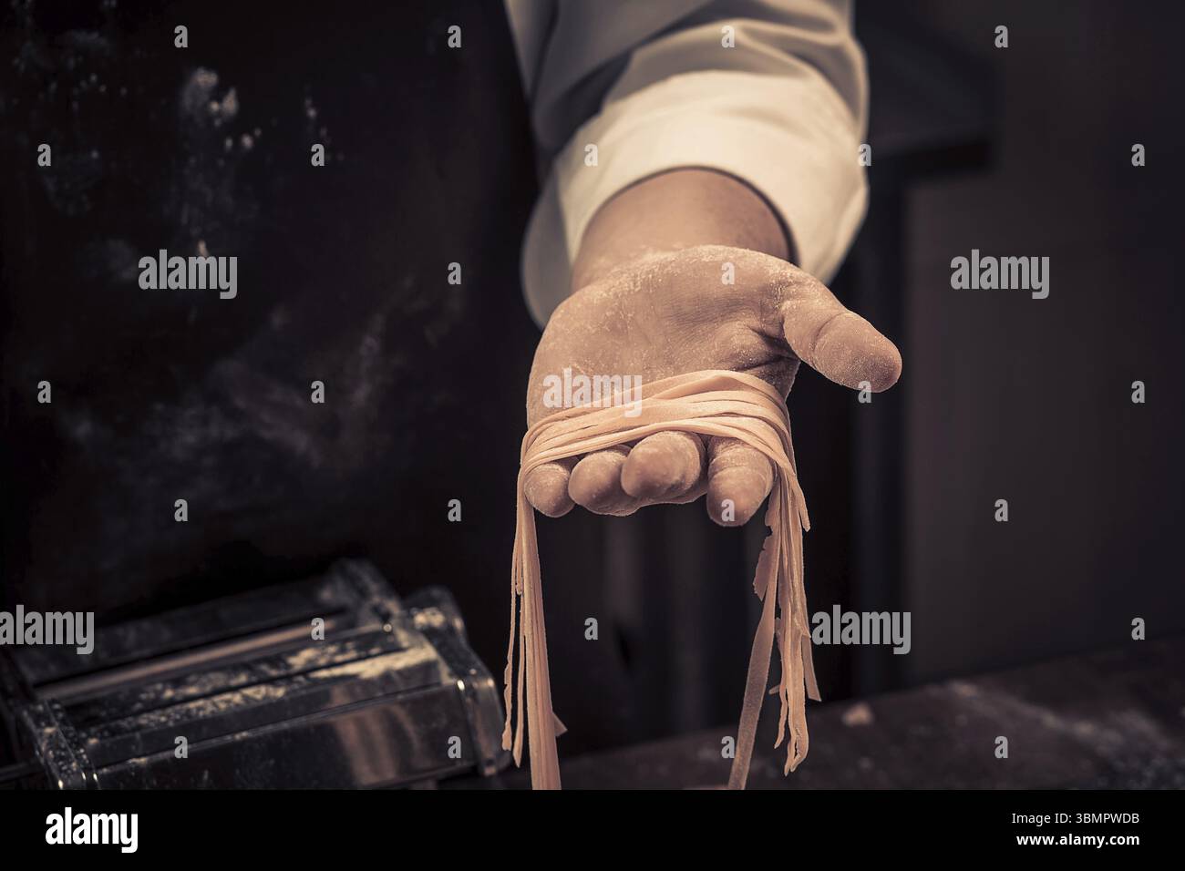 Der Koch bereitet frische Spaghetti von Grund auf zu. Holztisch. Foto in Brauntönen. Küche Stockfoto