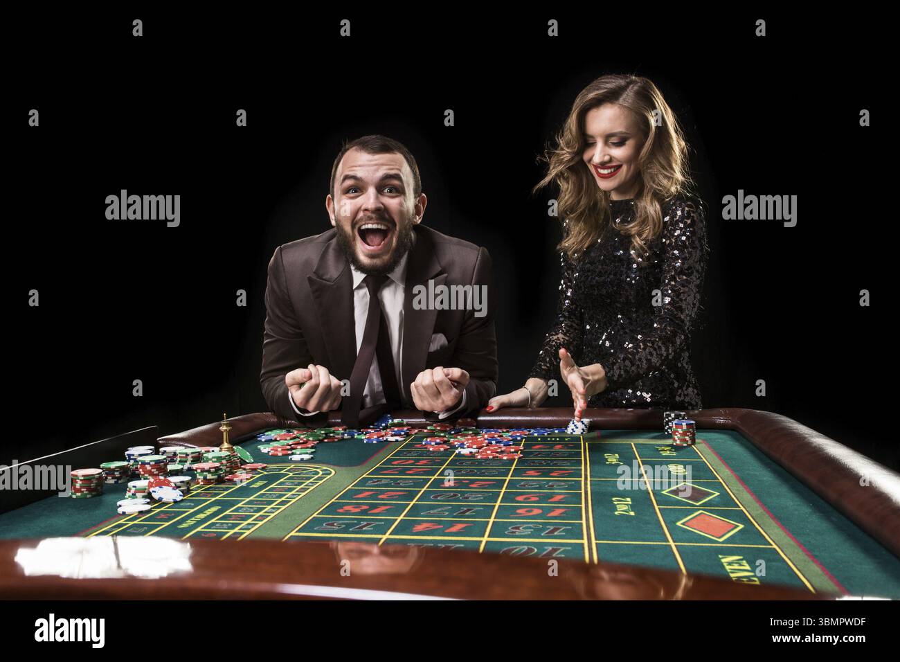 Ein Mann in einem Anzug mit einer Frau in einem schönen schwarzen Kleid, die Roulette im Casino spielt. Glücksspiel. Kasino. Roulette. Poker Stockfoto
