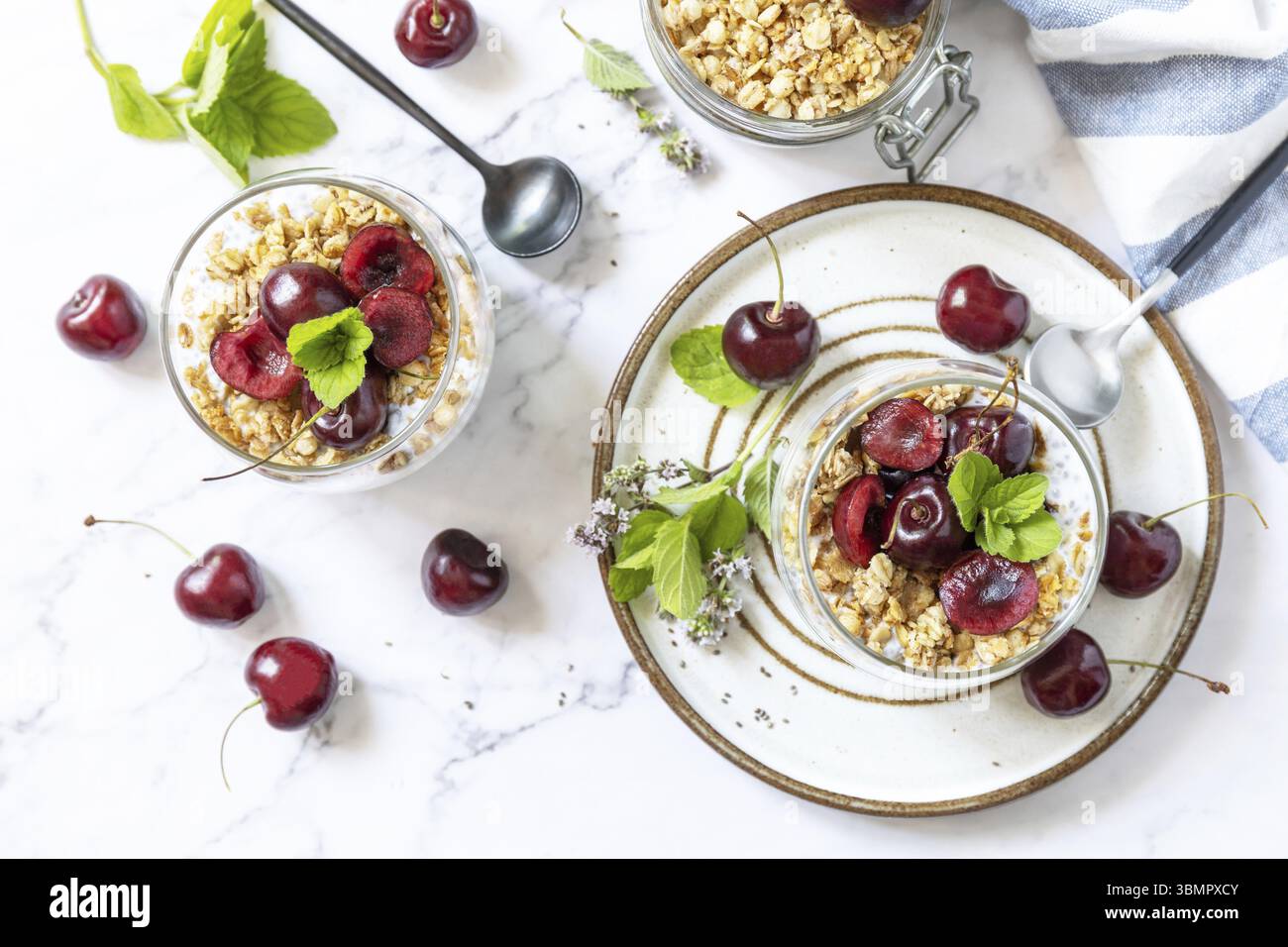 Gesundes Menükonzept. Hausgemachtes Müsli-Frühstück. Glas Parfait aus Müsli, Beerenkirsche, Joghurt mit Chiasamen auf rustikalem Tisch. Blick von Stockfoto