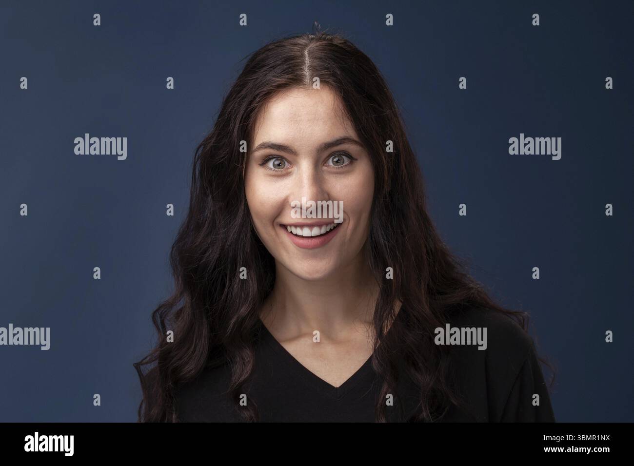 Porträt eines hübschen Mädchens mit professionellem Make-up, einem schwarzen T-Shirt, wundert und posiert auf grauem Hintergrund. Gesundes Ku Stockfoto