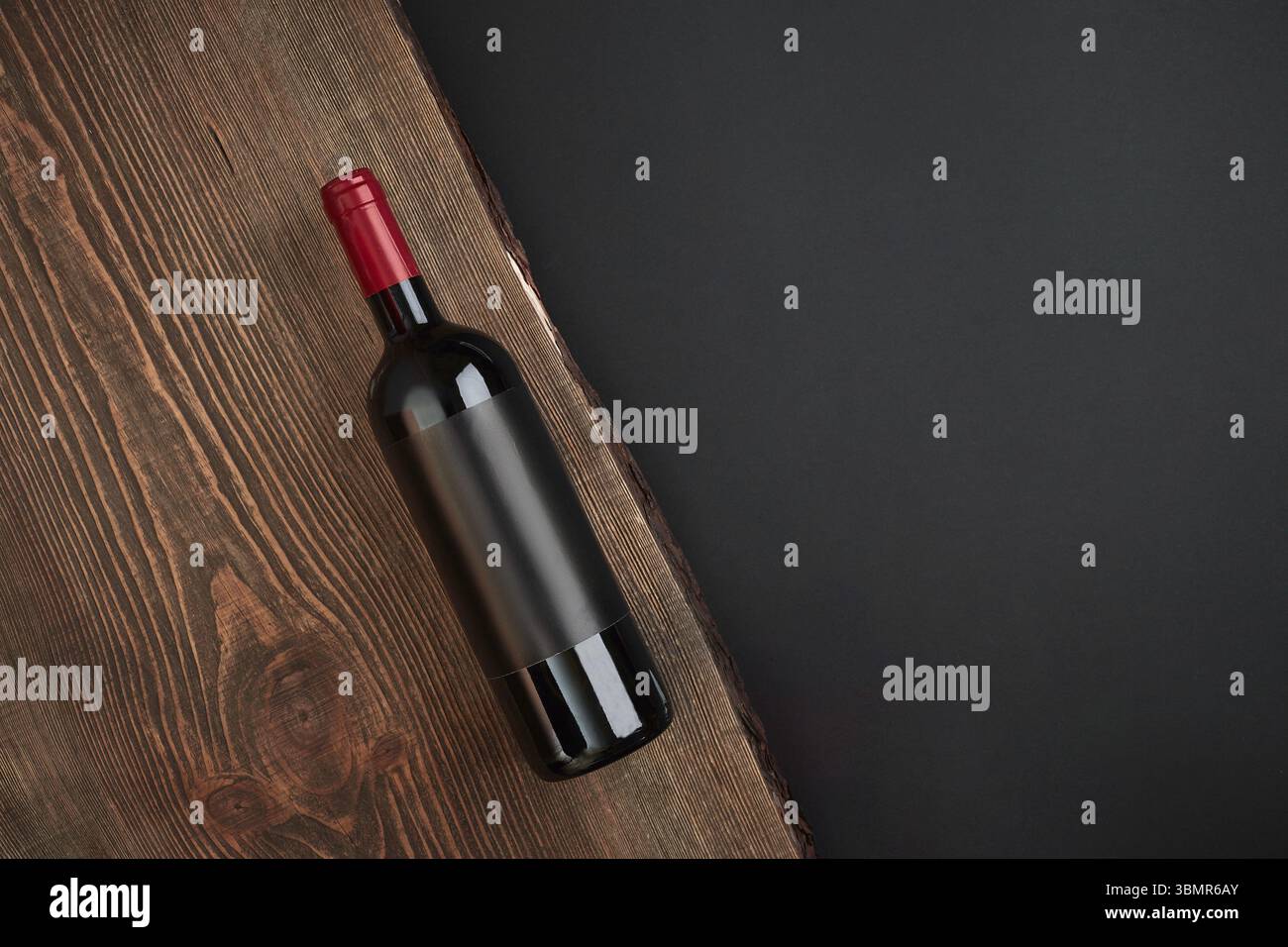 Flasche Wein auf der Holzplatte auf schwarzem Hintergrund. Ansicht von oben mit der Kopie. Immer noch leben. Flach Stockfoto
