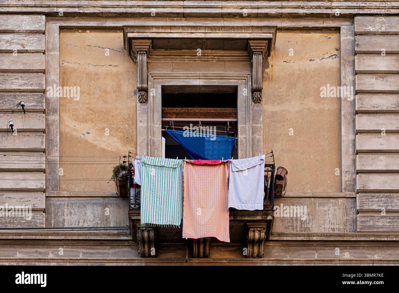 Authentische Szene des täglichen Lebens in Sizilien, mit Wäsche, die vom Balkon eines traditionellen alten Gebäudes zum Trocknen aufgehängt wird Stockfoto