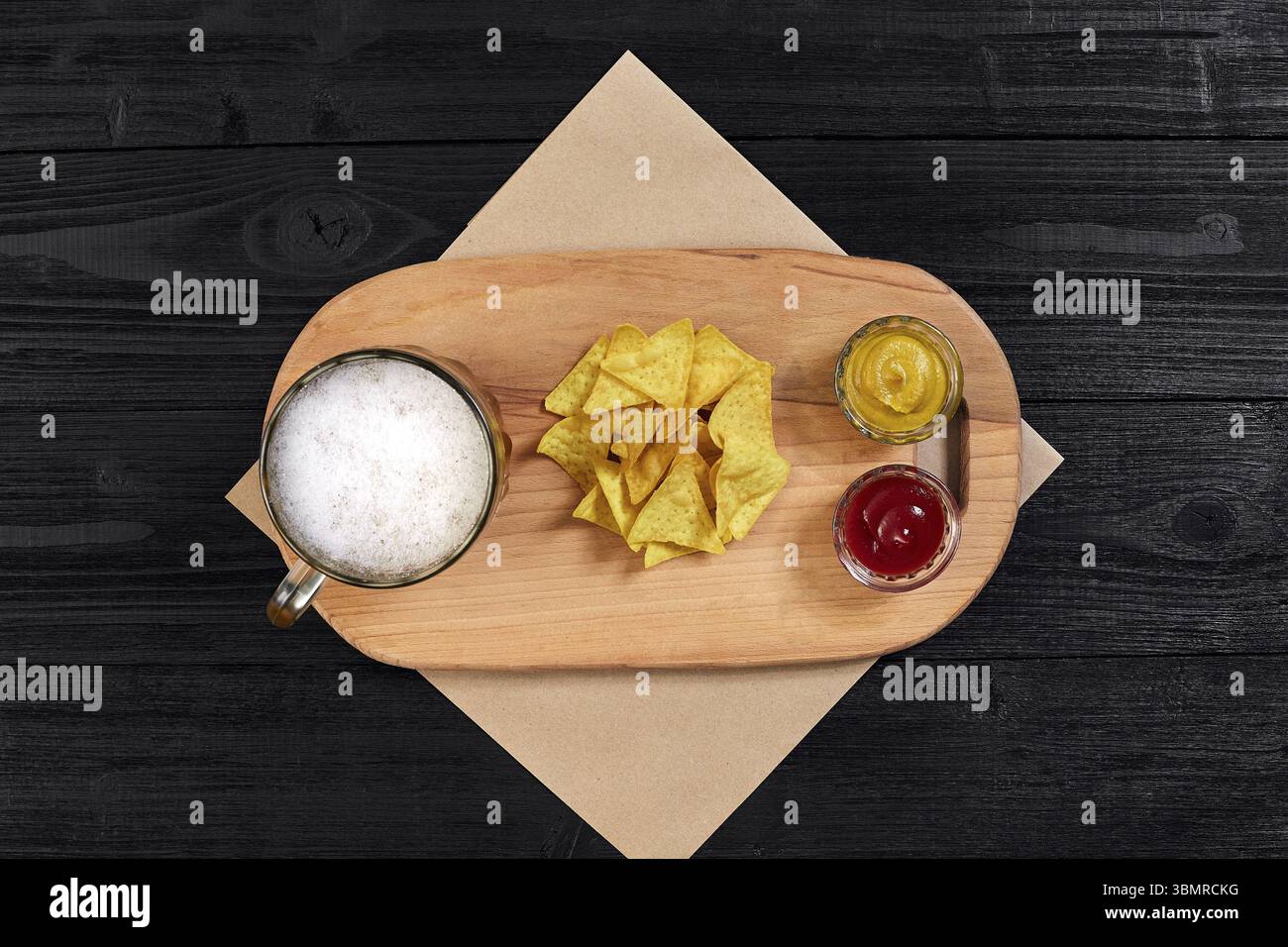 Glas Bier mit Nachos-Chips auf Holzhintergrund. Draufsicht. Speicherplatz kopieren. Stillleben. Flach liegend Stockfoto