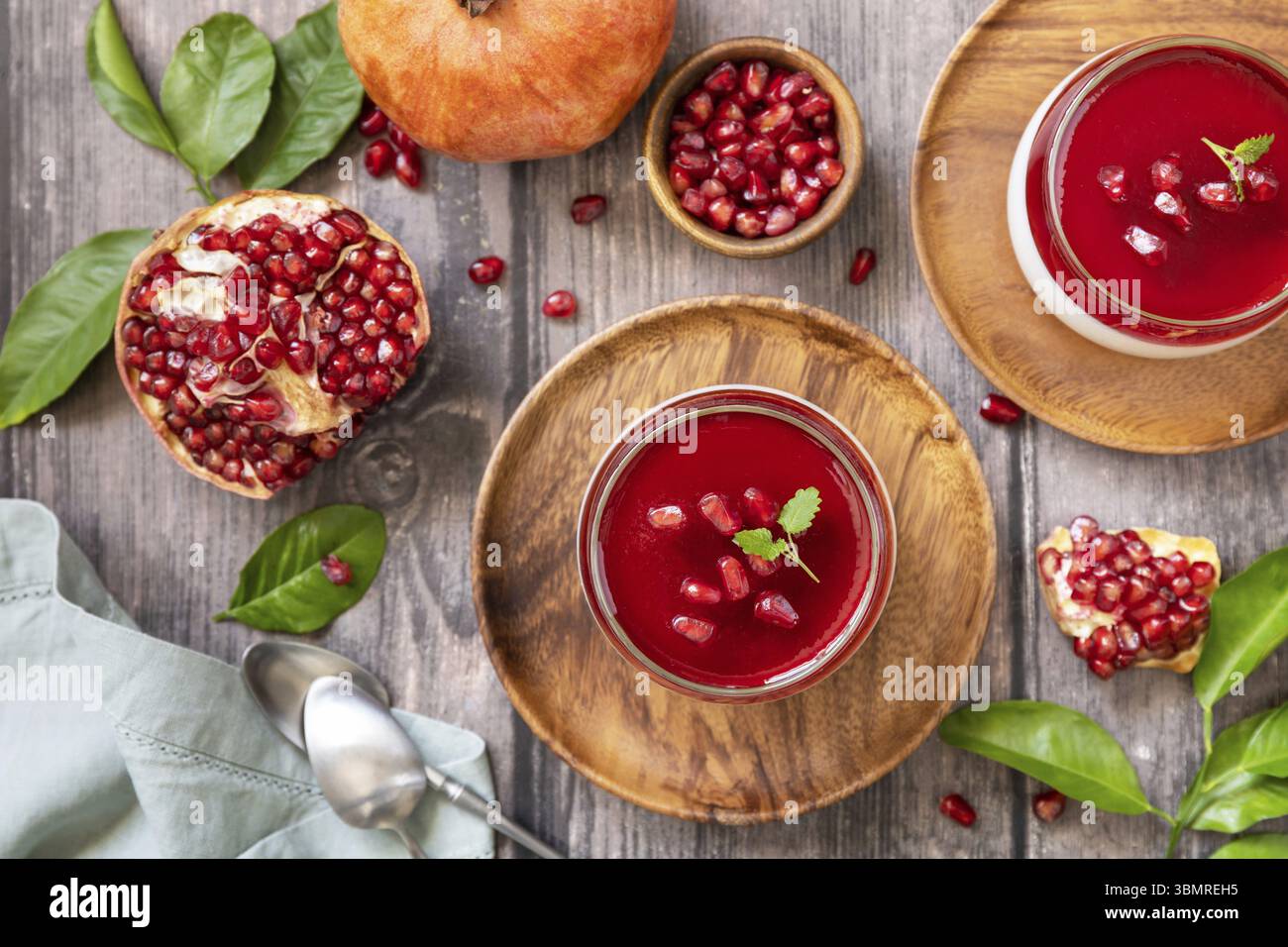 Winter köstliches italienisches Dessert Panna Cotta mit Granatapfelgelee und Minze, hausgemachte Küche auf hölzernem Hintergrund. Blick von oben Stockfoto