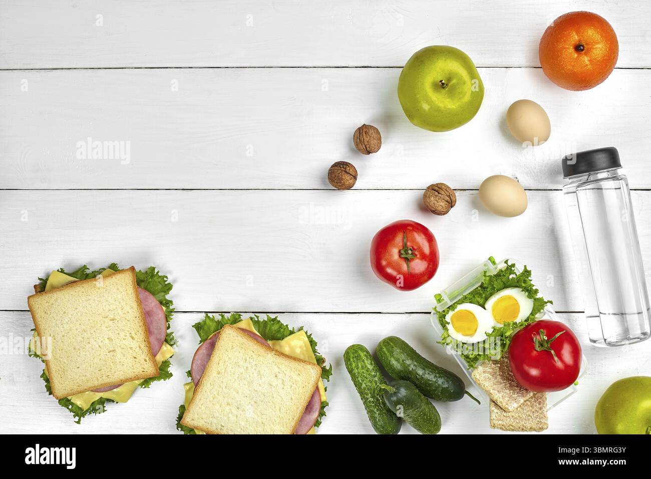 Mittagessen. Sandwich und frisches Gemüse, eine Flasche Wasser, Nüssen und Früchten auf weißem Holz- Hintergrund. Gesunde Ernährung Konzept. Ansicht von oben mit der Kopie. S Stockfoto