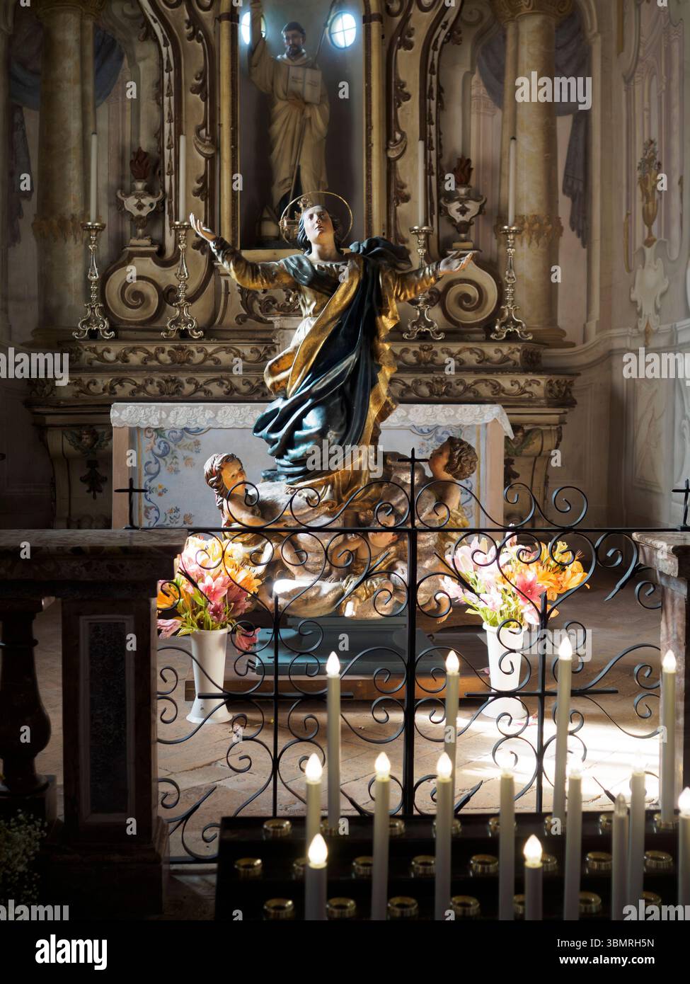 Alseno, Italien 22. Juni 2025 Goldene Jungfrau-Maria-Statue, die Schutzarme ausbreitet, darunter liegend, von Kerzenlicht in Chiaravall beleuchtet Stockfoto