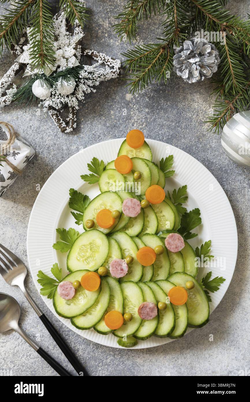 Weihnachtsbaum aus einem Salat olivier auf grauem Steinhintergrund. Vorspeise zu Weihnachten. Blick von oben Stockfoto