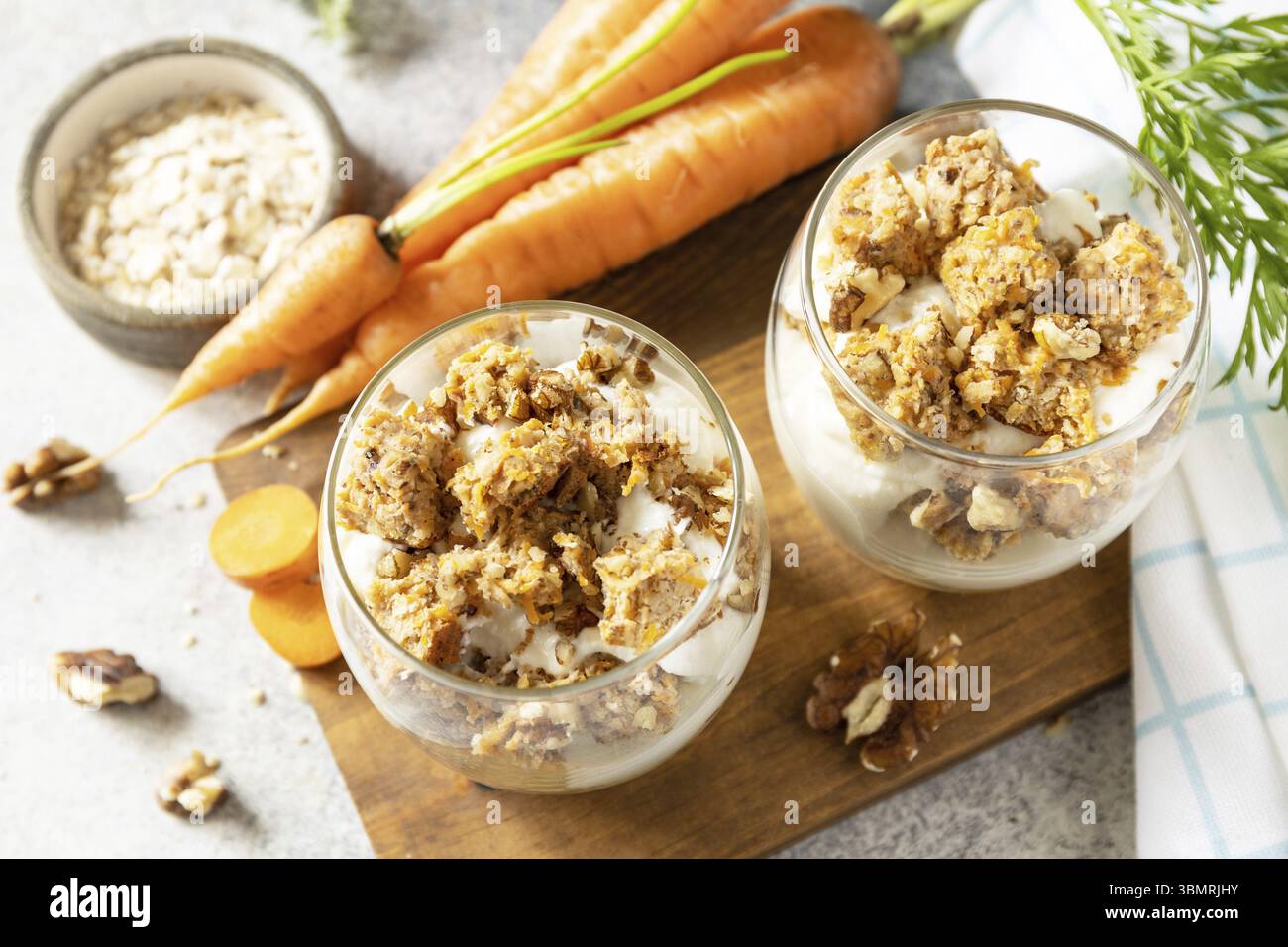 Veganes glutenfreies Backen. Karottenkuchen mit Walnüssen und Zimt in einem Glas auf hellem Hintergrund. Gesundes Dessert Stockfoto