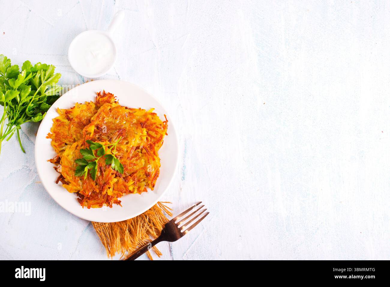 Gebratene Kartoffelpfannkuchen auf weißem Teller auf einem Tisch Stockfoto
