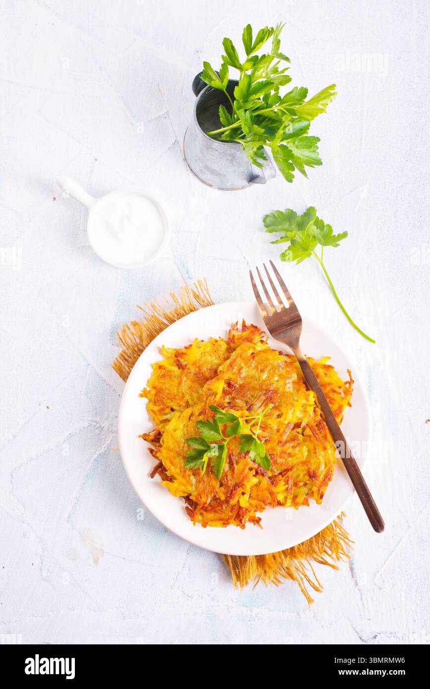 Gebratene Kartoffelpfannkuchen auf weißem Teller auf einem Tisch Stockfoto