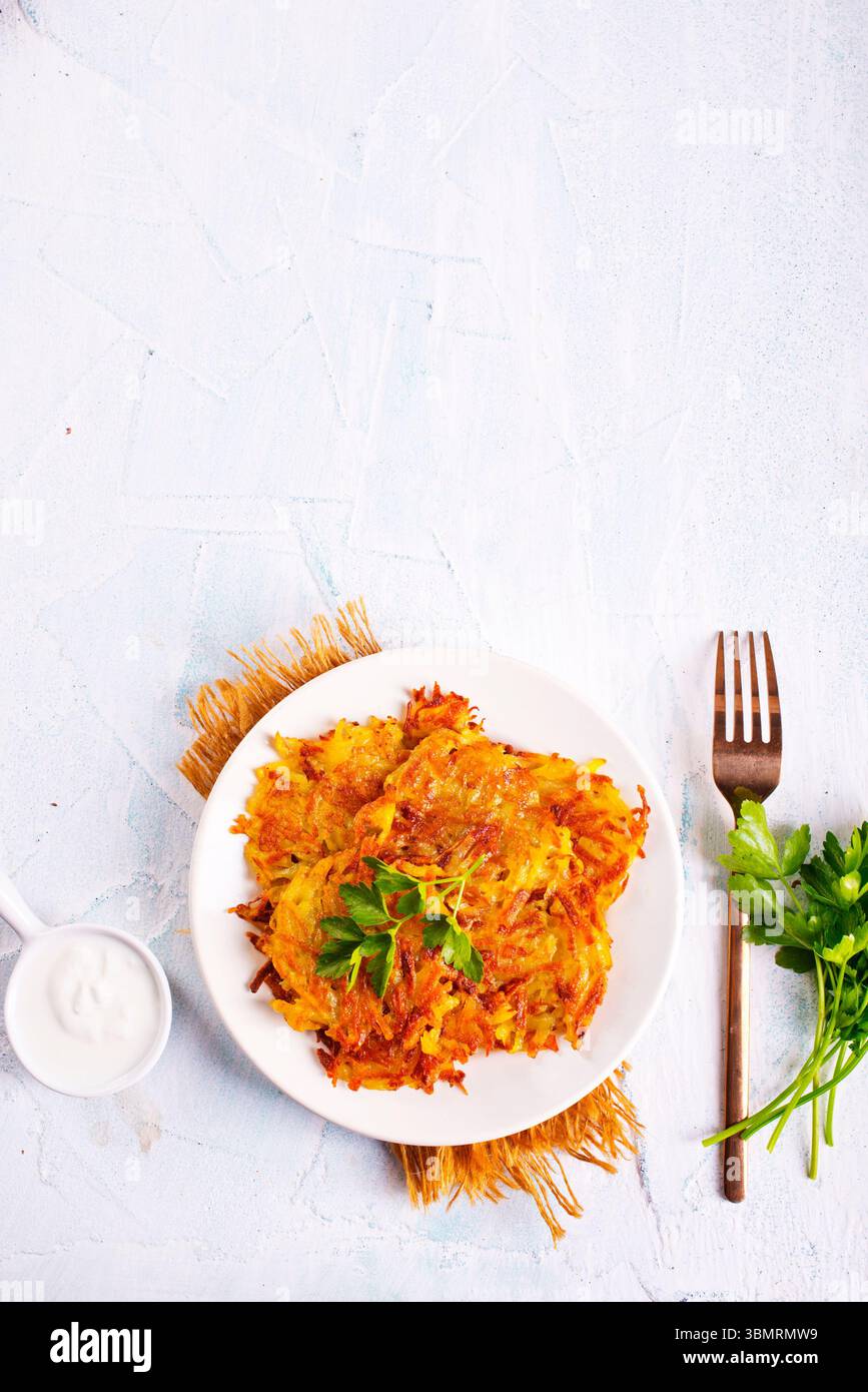 Gebratene Kartoffelpfannkuchen auf weißem Teller auf einem Tisch Stockfoto
