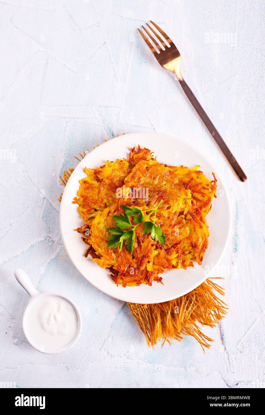 Gebratene Kartoffelpfannkuchen auf weißem Teller auf einem Tisch Stockfoto