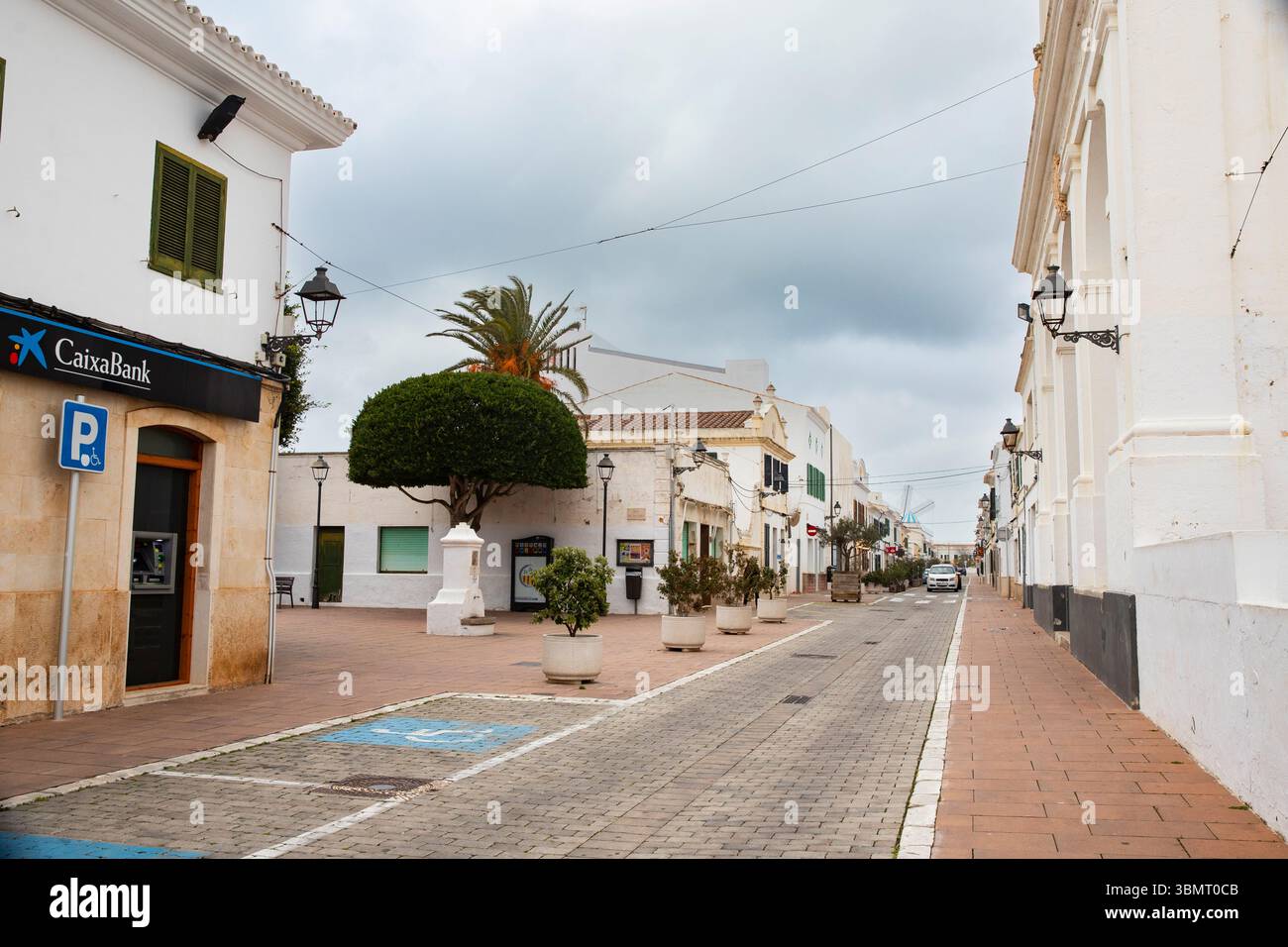 Ruhige Stadtlandschaft typische Architektur mit weißen Häusern auf der Insel. Straße mit Bank und traditionellen Gebäuden in Menorca, Spanien. 08.03.2025 Stockfoto
