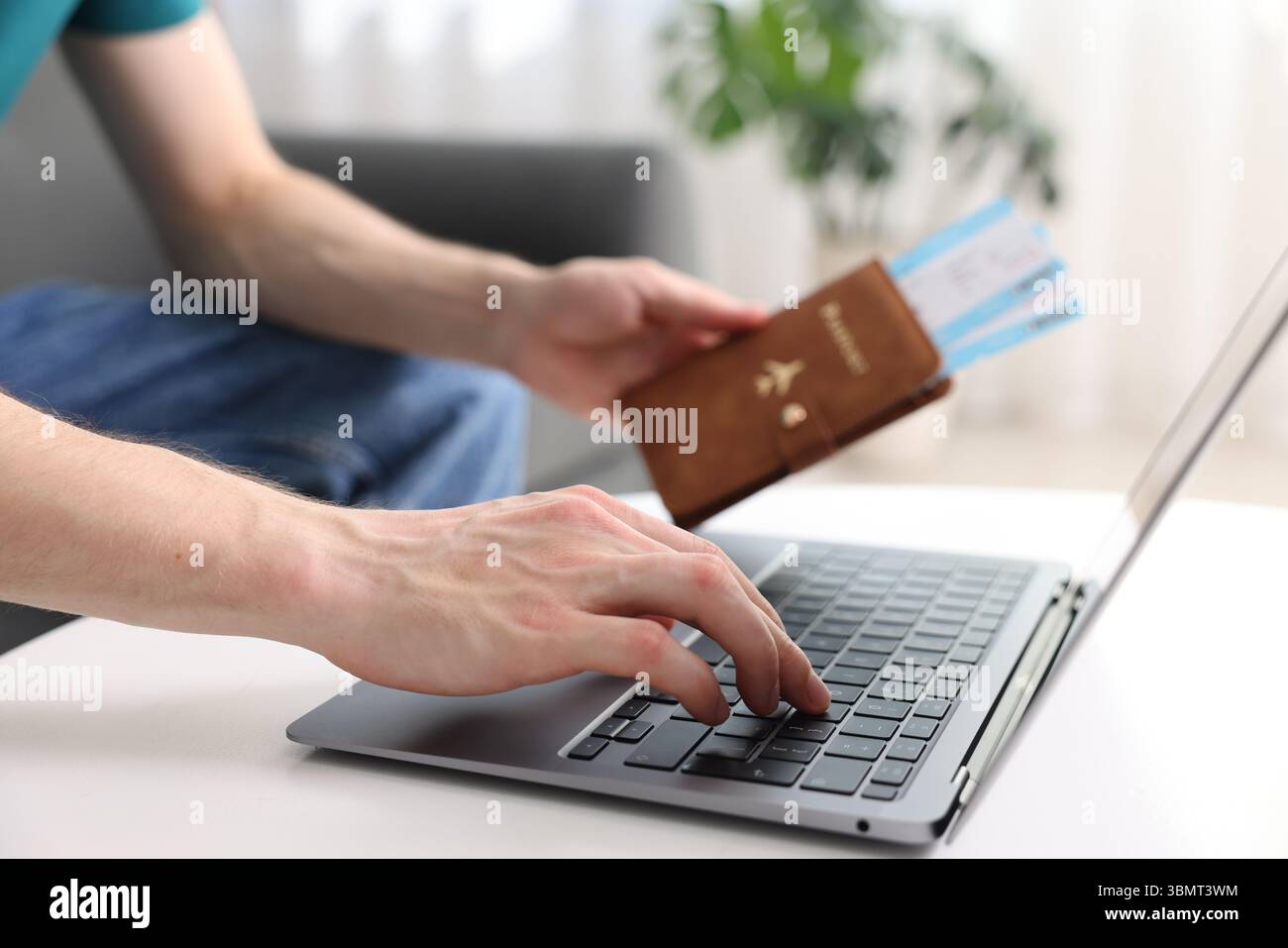 Mann mit Reisepass und Flugtickets mit Laptop drinnen, Nahaufnahme Stockfoto