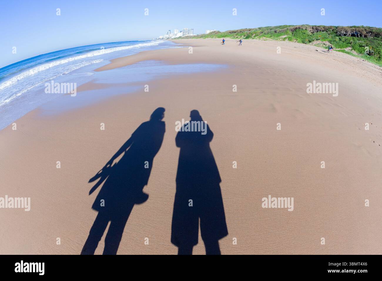 Mann, Frau, die am Strand läuft, Ozeangewässer, Schatten-Bilder auf der Sandküstenlandschaft. Stockfoto