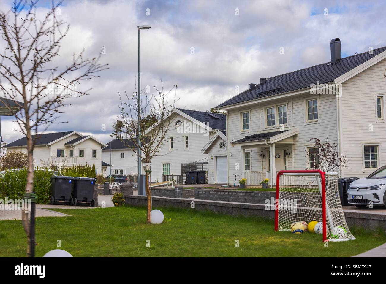 Moderne weiße europäische Villen mit Fußballtor auf grünem Rasen vor dem Hintergrund des bewölkten Frühlingshimmels. Schweden. Stockfoto