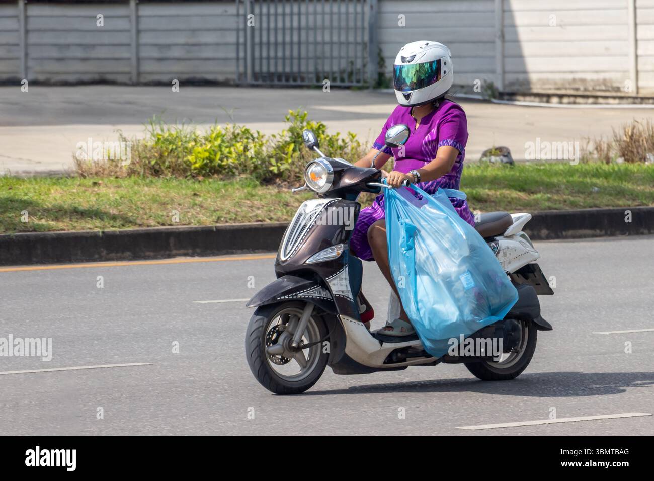 Eine Frau mit großem Plastiksack, die Motorrad fährt, Thailand Stockfoto