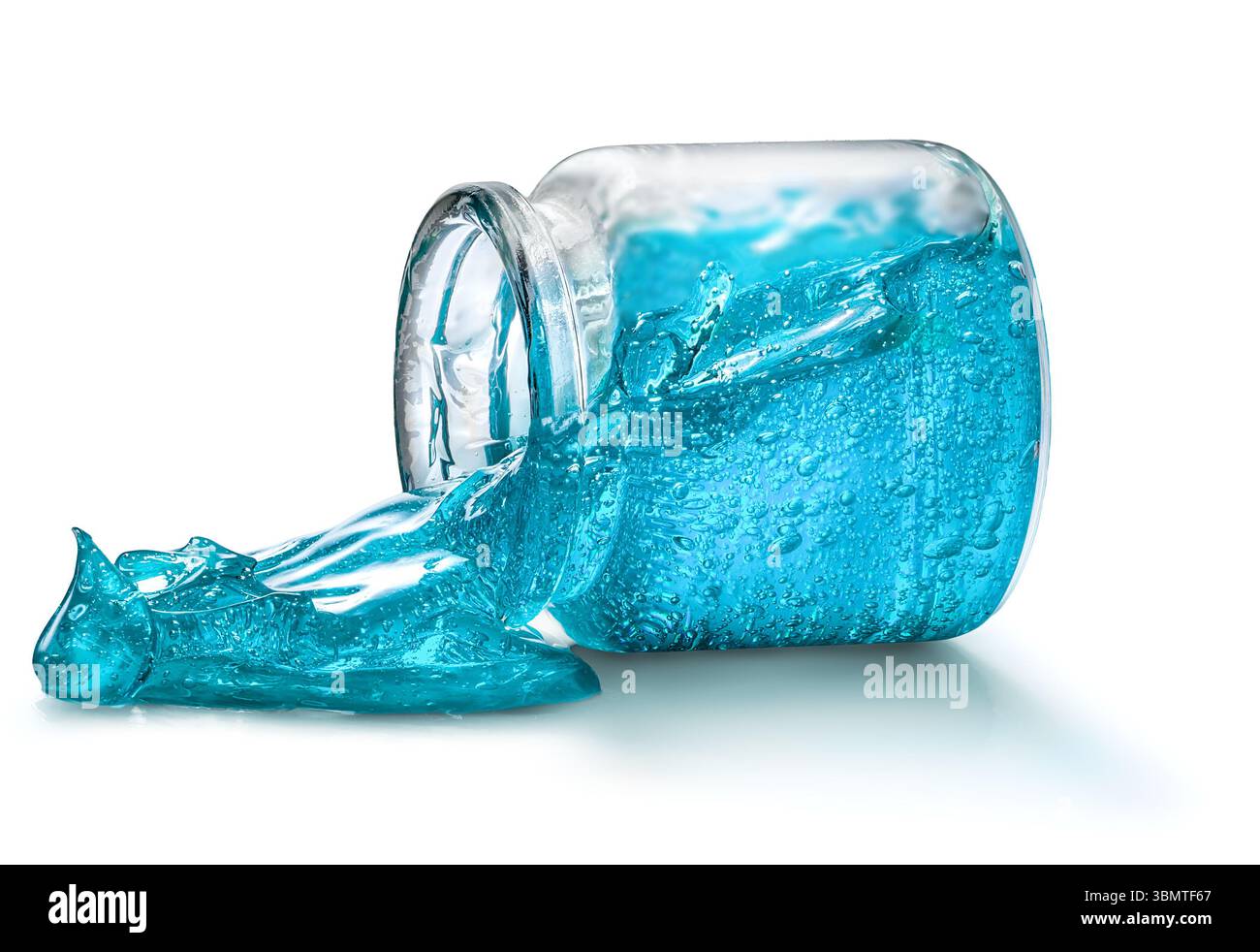 Ein hellblaues Haarstyling-Gel wird aus einem Glasbecher ausgeschüttet und zeigt seine leuchtende Farbe und einzigartige Textur auf weißem Hintergrund Stockfoto