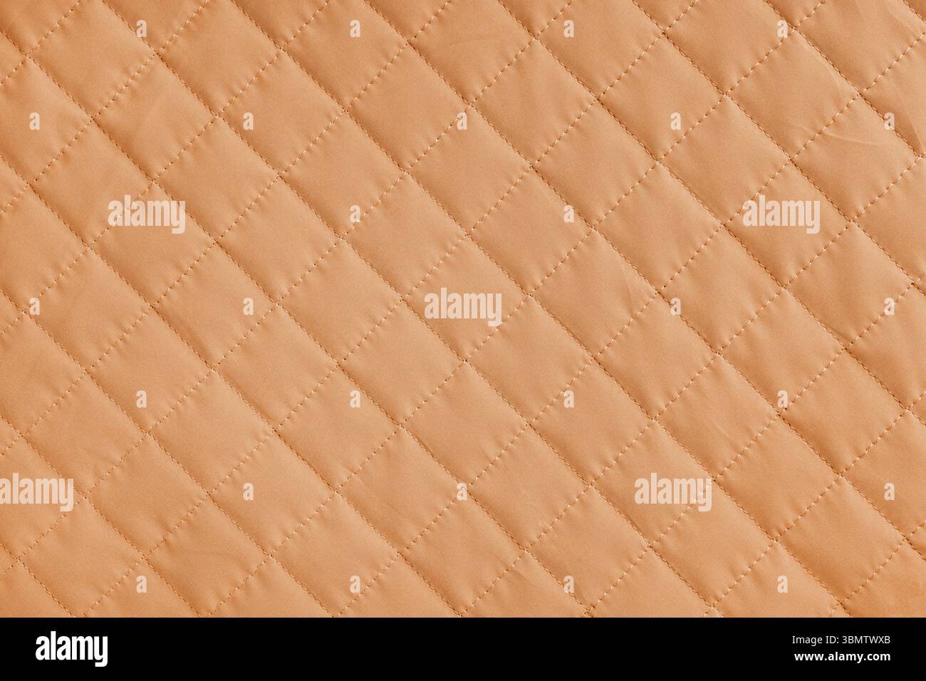 Kariertes Rautenmuster, orangefarbener gesteppter Stoffhintergrund. Decke oder Pufferjacke, Naht Rautenstruktur Nahaufnahme, Makro. Hintergrundbild, b Stockfoto