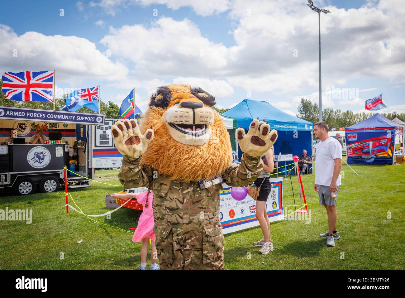 Warrington, Großbritannien, 28. Juni 2025 – Crosfields Rugby Amateur Rugby League Football Club Ground war die Bühne des jährlichen Armed Forces Day in Warrington. Die britischen Streitkräfte nahmen an der jährlichen Tom Sephton Memorial Trophy Teil, einem Rugby League-Turnier in Gedenken an Tom Sephton vom 1. Bataillon des Mercian Regiments, der tragischerweise an Wunden starb, die während des Dienstes in Afghanistan erlitten hatten. Das Festival umfasst verschiedene Gemeindegruppen, Rettungsdienste sowie Stände der Streitkräfte. Die Armed Forces Community Support Group trägt ein getarntes Britisches Löwenkostüm. Stockfoto