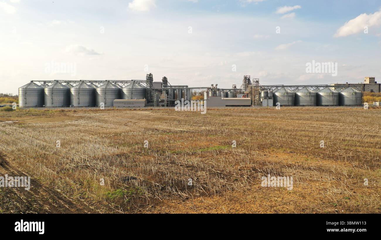 Moderner Getreideaufzugskomplex vor ländlichem Hintergrund, in dem die landwirtschaftliche Infrastruktur und die Prozesse der Lebensmittelproduktion hervorgehoben werden Stockfoto