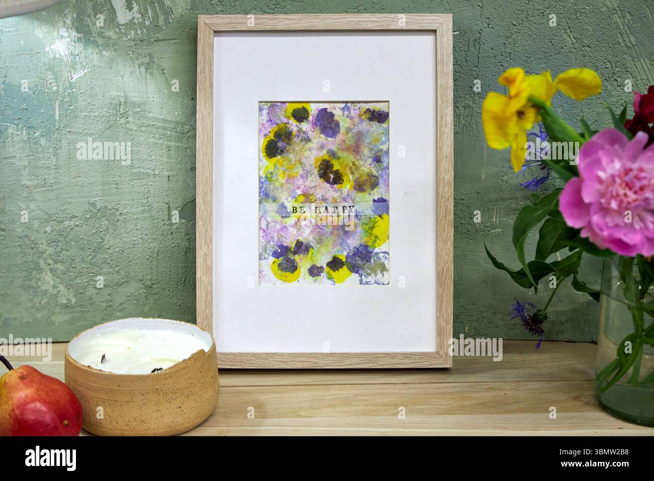 Gerahmter botanischer Druck mit „Be Happy“-Text im gemütlichen Innenraum – natürliche Blütenpigmente, handgefertigte Blumenkunstwerke, rustikale Wanddekoration Stockfoto