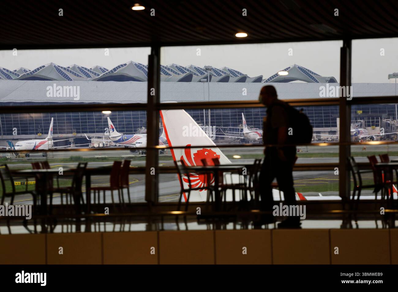 Kuala Lumpur, Malaysia - 6. Dezember 2022: Silhouette eines Passagiers, der durch den internationalen Flughafen KLIA läuft. Batik Malindo und Malaysia Airlines. Stockfoto