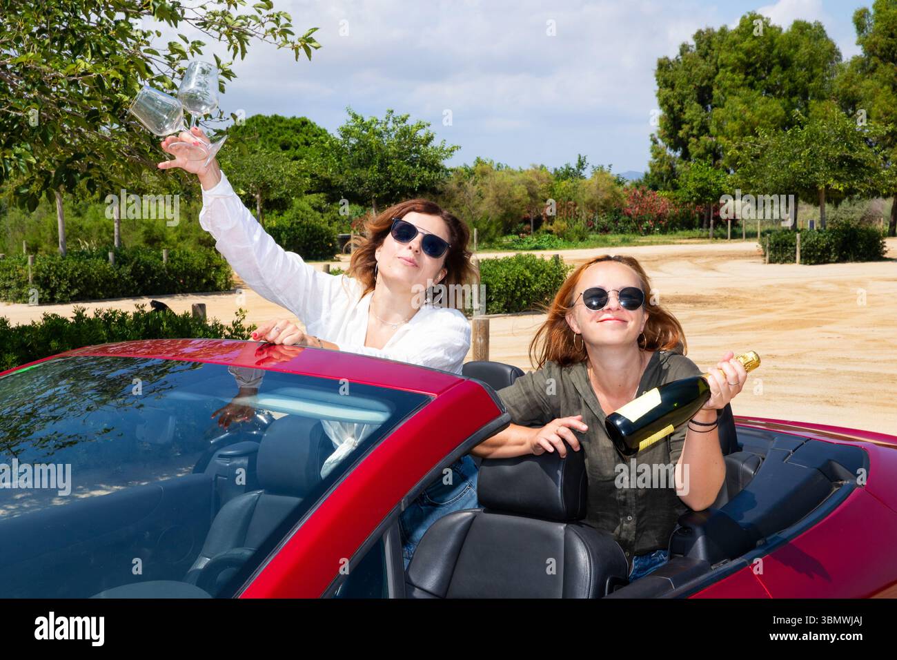 Freundinnen in einem roten Cabrio feiern Sommer und Freiheit Stockfoto