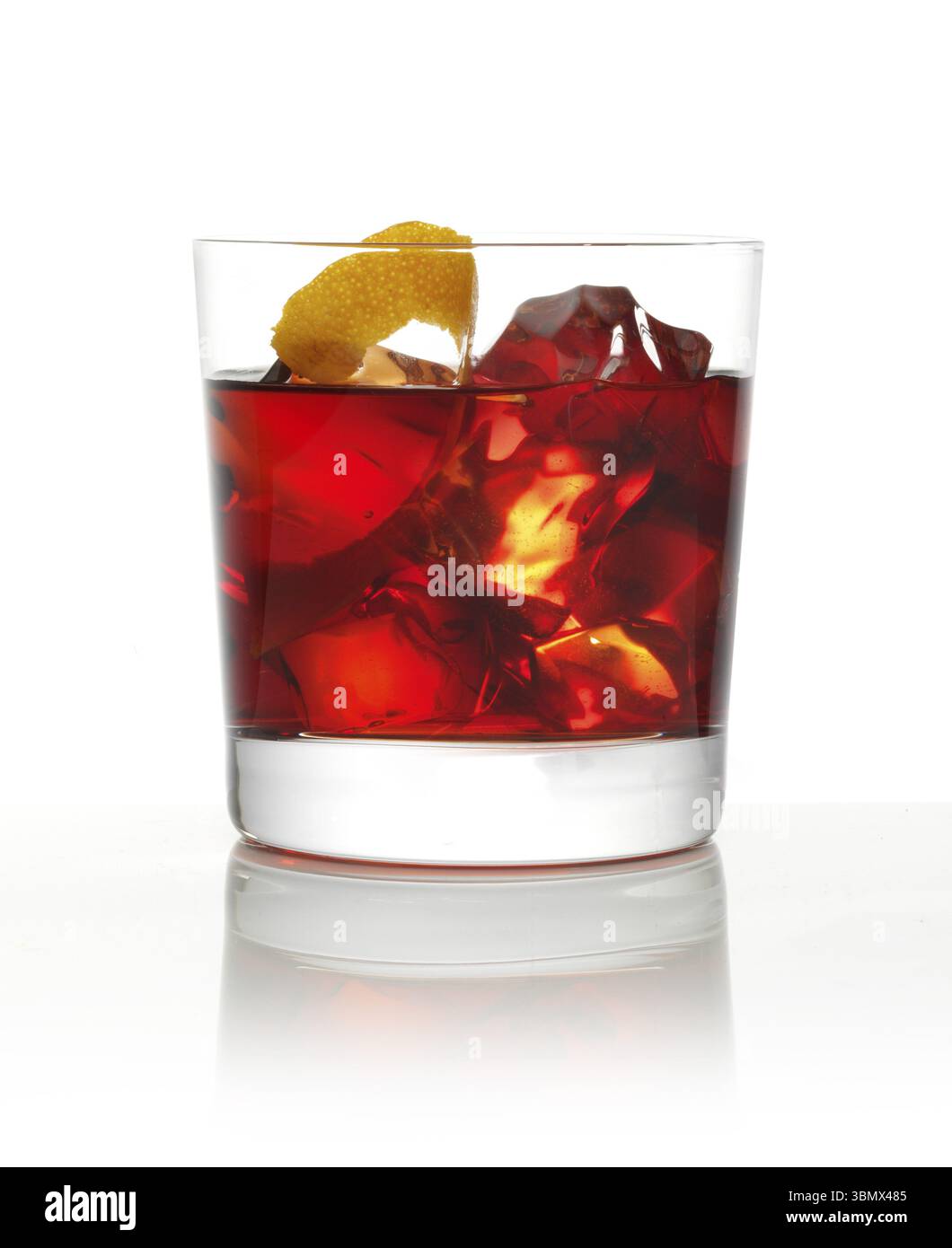 Cocktail in einem Tumbler auf Eis mit einer Orangenschale als Garnitur vor weißem Hintergrund, Studio-Aufnahme Stockfoto