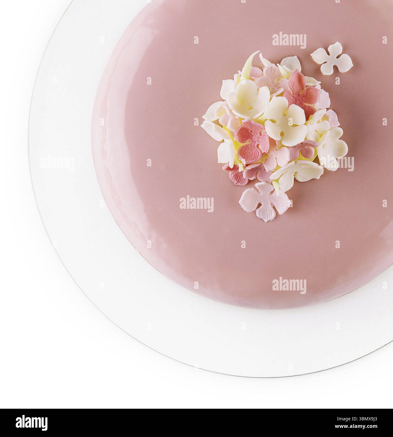 Stillleben, rosafarbener Mousse-Kuchen mit Spiegelglasur, dekoriert mit Blumen Stockfoto